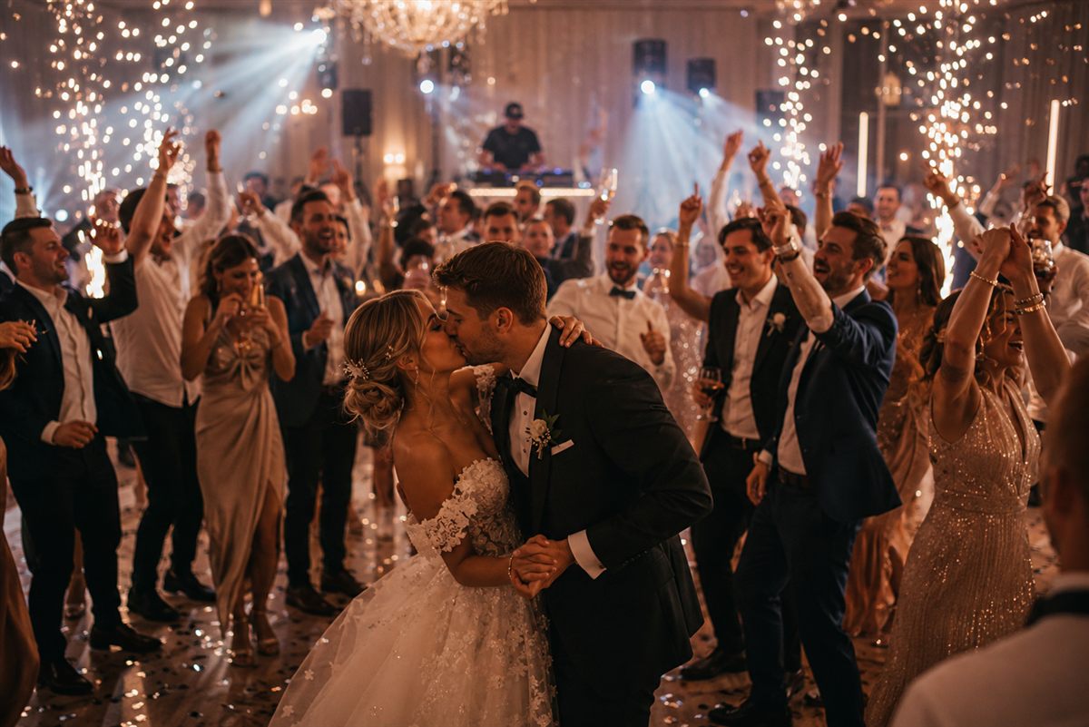 Hochzeitspaar und Gäste mit DJ bei einer Feier