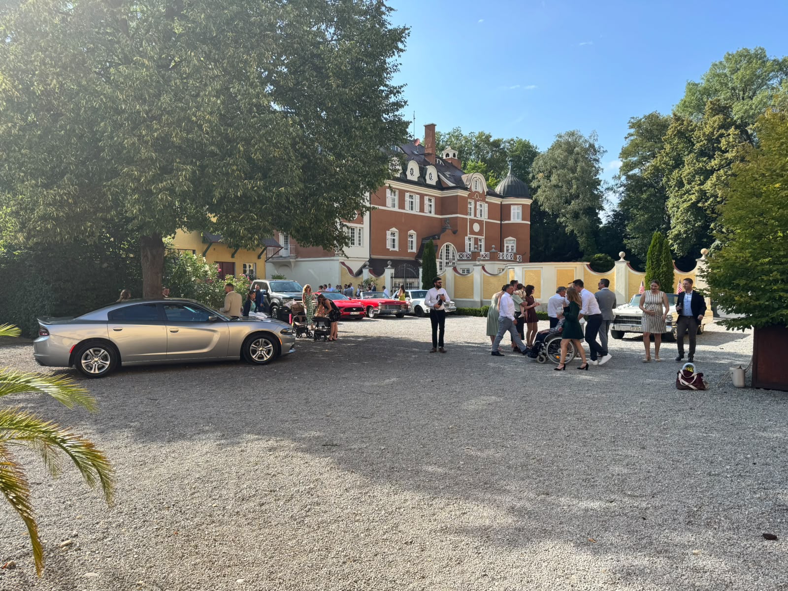 Hochzeitsgäste und amerikanische Autos vor dem Gut Schwabhof bei Augsburg