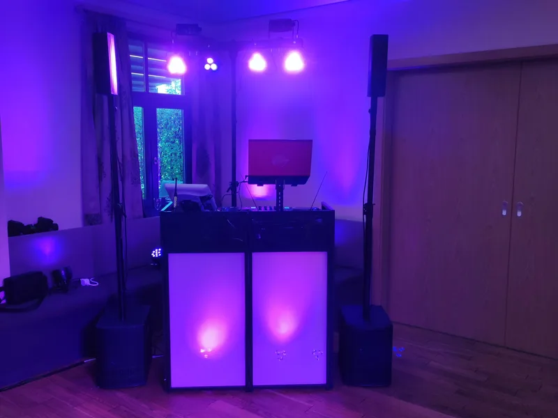 DJ-Setup mit lila und pinkfarbenem Uplighting im Veranstaltungsraum am Abend – Hochzeits DJ Rico Cinsano