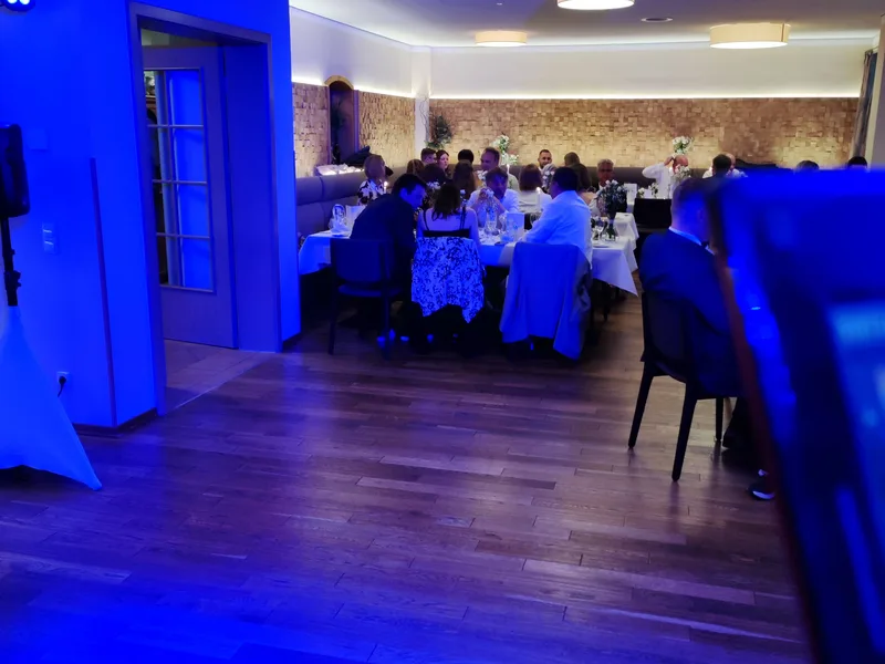 Hochzeitsgesellschaft beim Dinner im festlich beleuchteten Saal mit blauem Uplighting – Hochzeits DJ Rico Cinsano