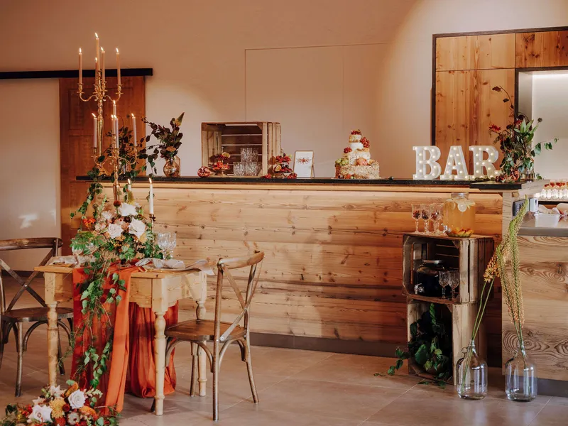 Grafenstadl Bar-Bereich Herbst-Hochzeit – leuchtendes BAR-Schild, Hochzeitstorte, goldener Kerzenleuchter und Herbst-Tischdeko