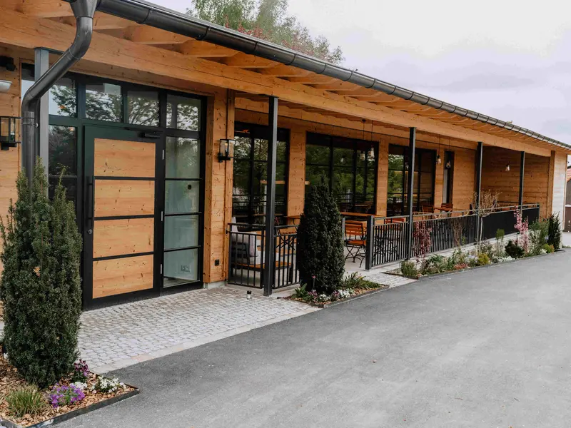 Grafenstadl Außenansicht – moderner Holzbau mit Panoramafenstern, Terrasse und Kopfsteinpflaster-Eingang