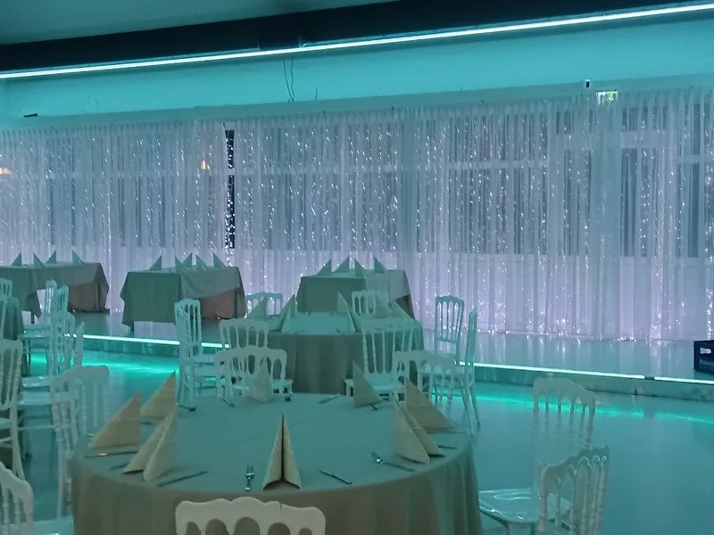 Royal am See Friedberg · Saal mit türkisem Ambientelicht und eingedeckten Tischen